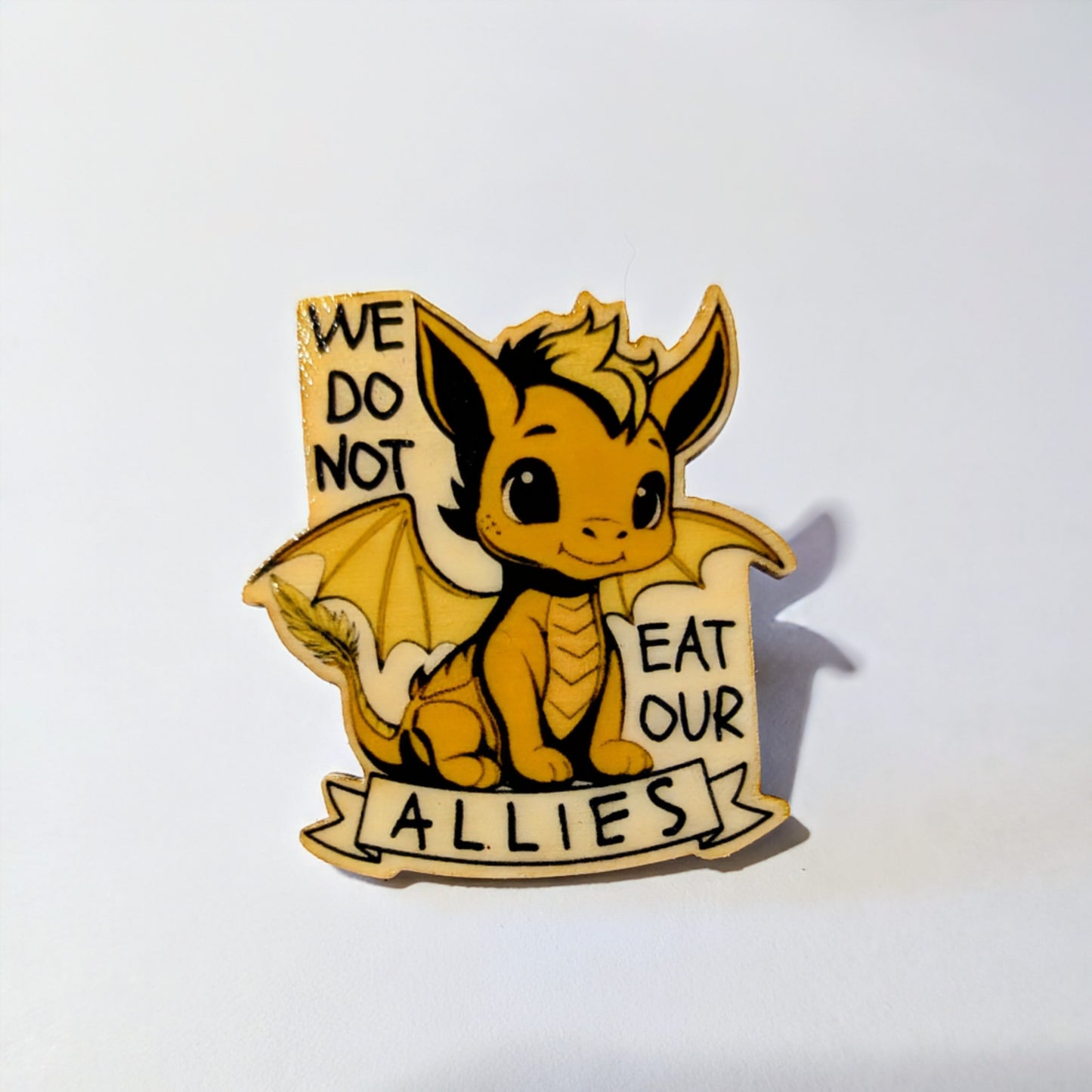 Andarna The Golden Dragon pin with text 'We do not eat our allies' on a white background. From Rebecca Yarros series Fourth Wing. Feathertail dragon